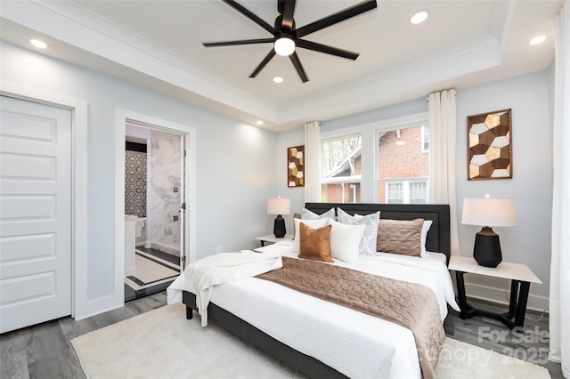 bedroom featuring ensuite bath, wood-type flooring, a raised ceiling, and ceiling fan