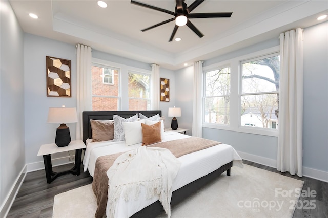 bedroom featuring dark wood-type flooring, a raised ceiling, and multiple windows