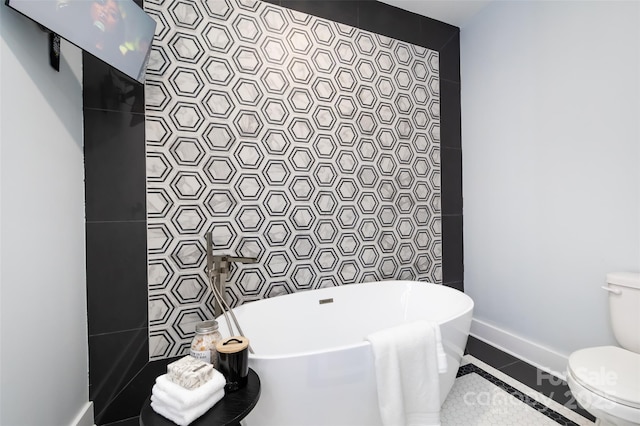 bathroom featuring tile patterned floors, toilet, tile walls, and a tub