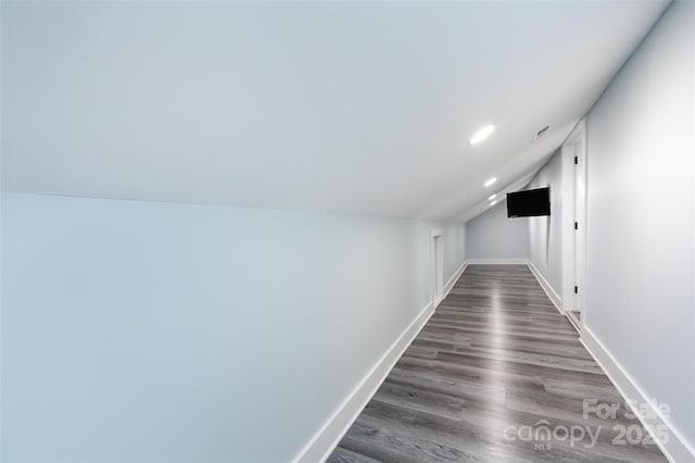 corridor with vaulted ceiling and dark hardwood / wood-style floors