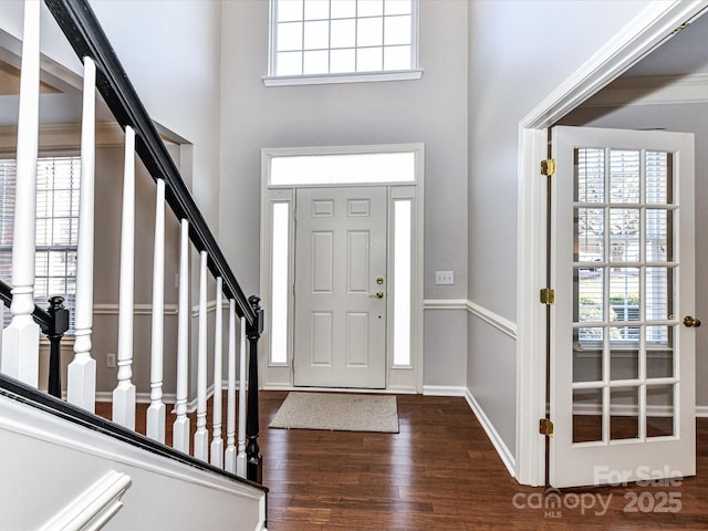 foyer entrance featuring dark wood-type flooring, a wealth of natural light, and a towering ceiling