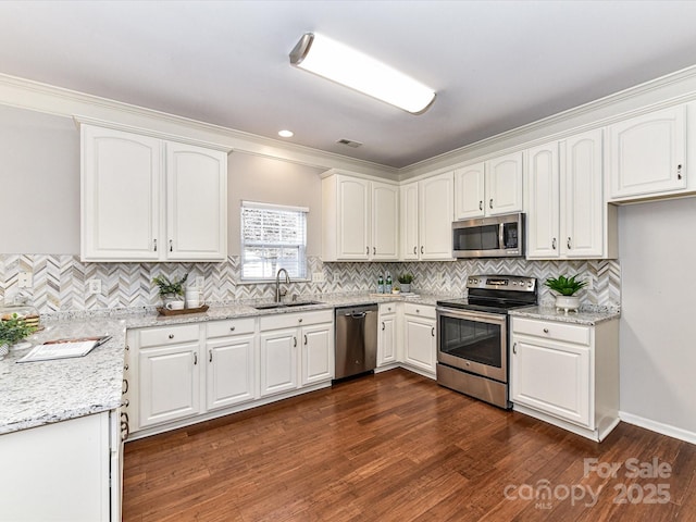 kitchen with dark wood-style flooring, stainless steel appliances, white cabinetry, a sink, and light stone countertops