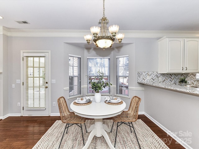 dining space featuring visible vents, dark wood-type flooring, a notable chandelier, and ornamental molding