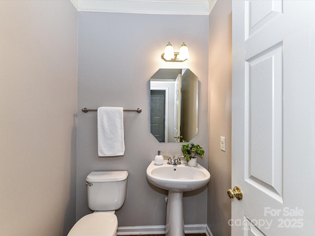 half bath featuring ornamental molding, a sink, toilet, and baseboards