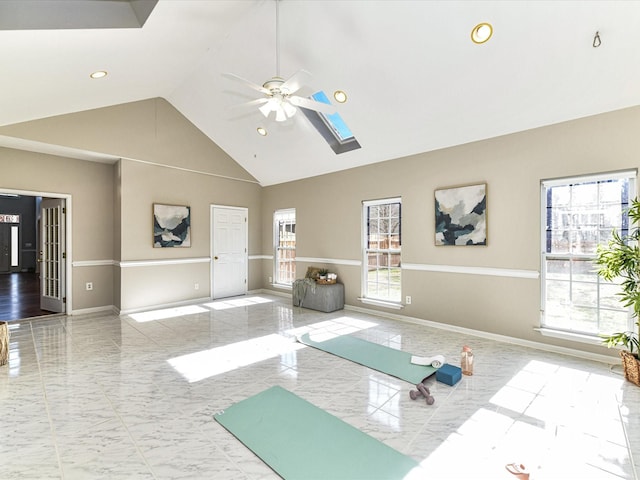 exercise area featuring ceiling fan, marble finish floor, a skylight, and baseboards