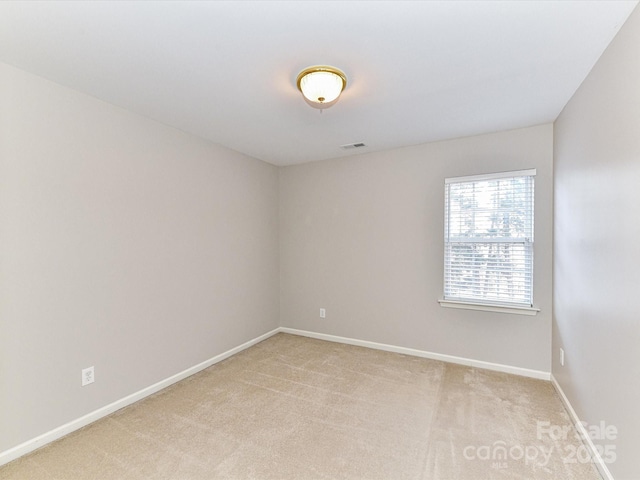 empty room with baseboards, visible vents, and light colored carpet