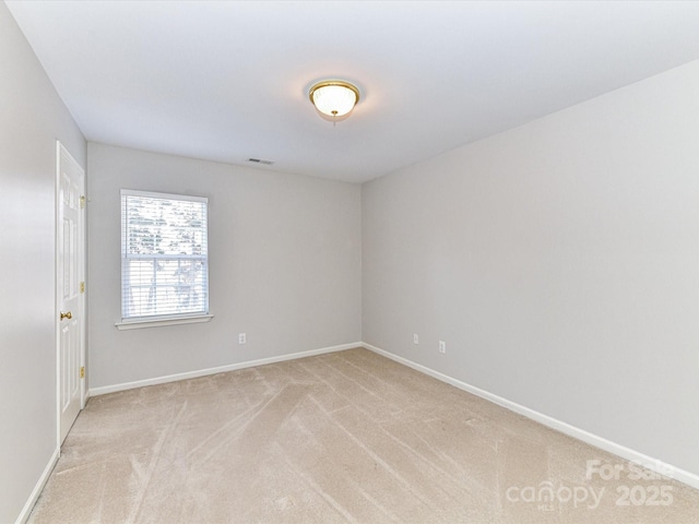 spare room with light carpet, visible vents, and baseboards