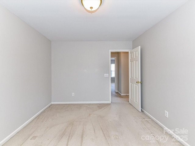 spare room with baseboards and light colored carpet