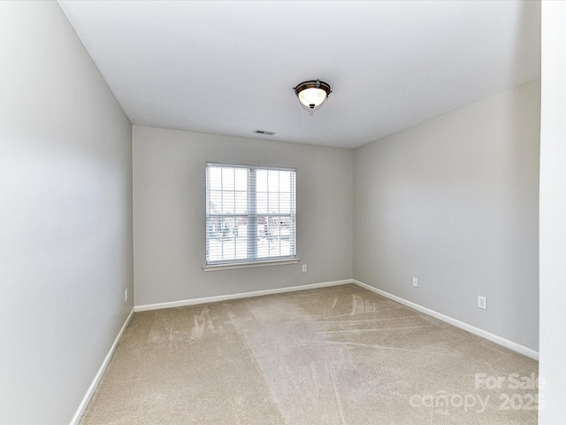 unfurnished room with carpet, visible vents, and baseboards