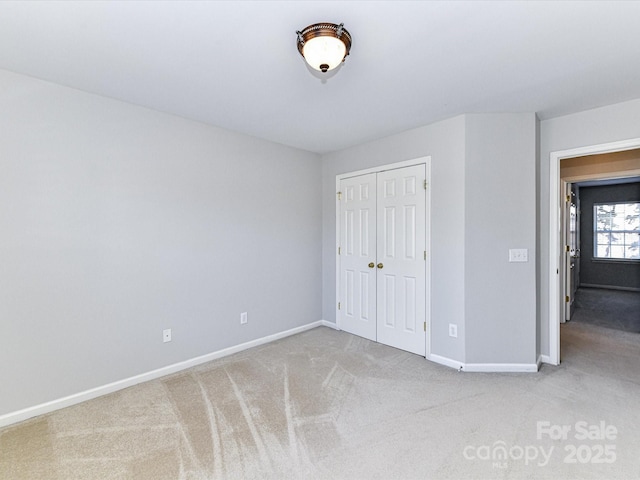 unfurnished bedroom with a closet, carpet flooring, and baseboards