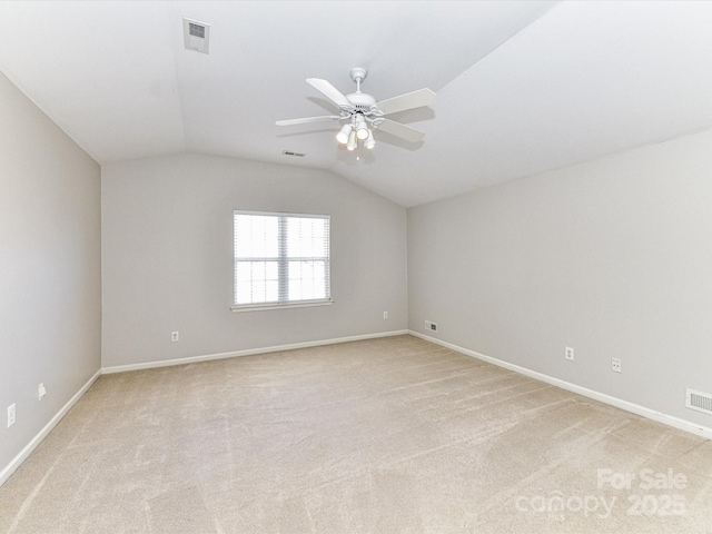 spare room featuring visible vents, a ceiling fan, light carpet, vaulted ceiling, and baseboards