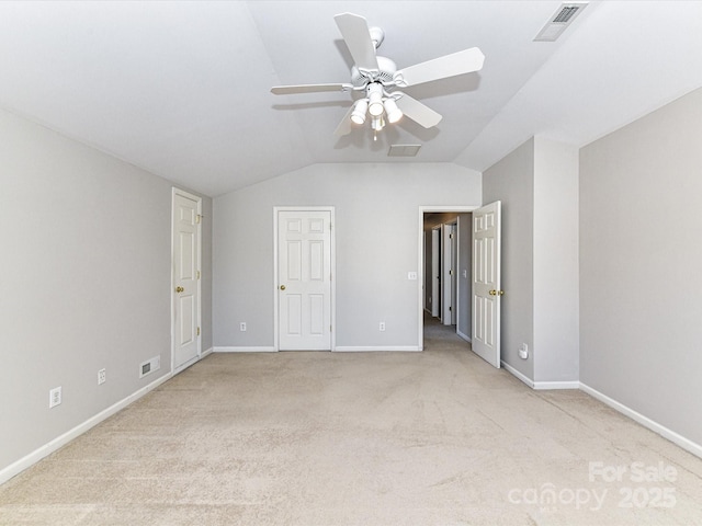 unfurnished bedroom with light colored carpet, lofted ceiling, visible vents, and baseboards