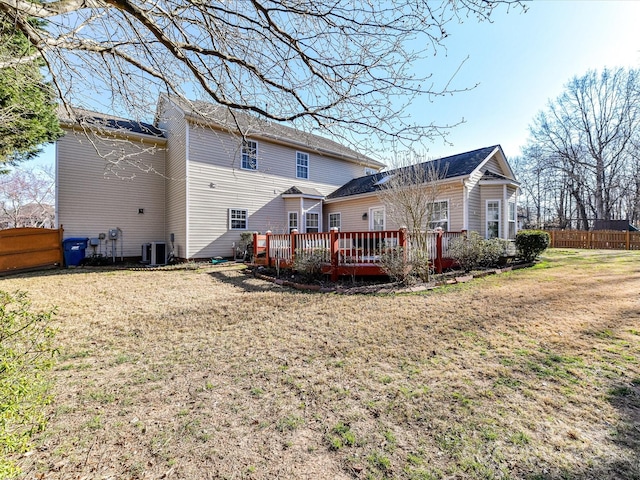 back of house featuring cooling unit, fence, a deck, and a lawn