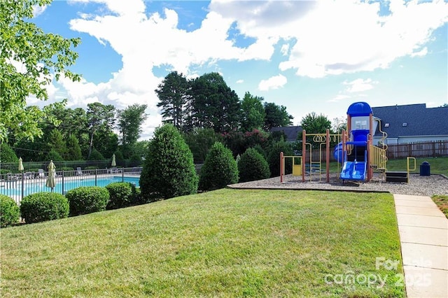 community jungle gym with a community pool, fence, and a yard