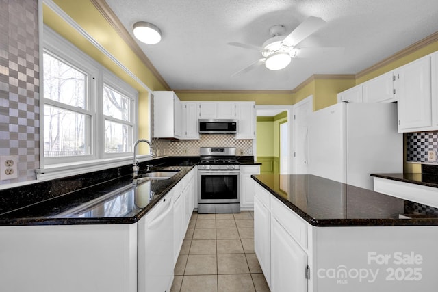 kitchen with light tile patterned flooring, sink, dark stone countertops, appliances with stainless steel finishes, and white cabinets