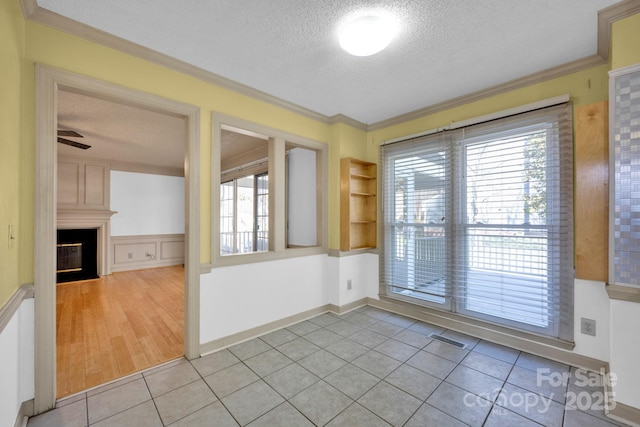 interior space featuring crown molding, built in features, a fireplace, and a textured ceiling