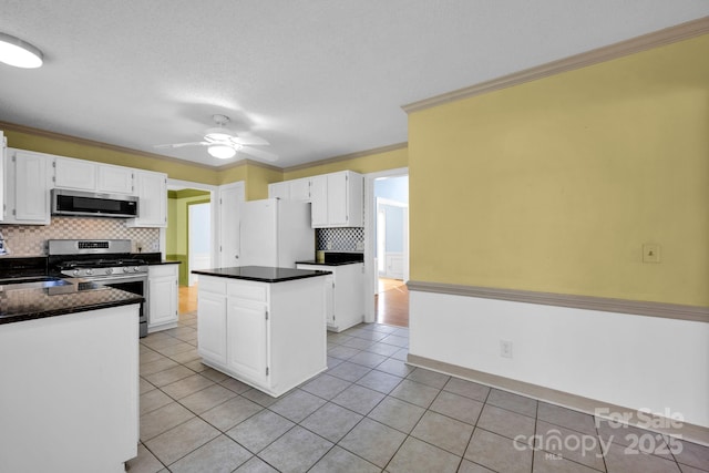 kitchen featuring crown molding, light tile patterned floors, appliances with stainless steel finishes, a kitchen island, and white cabinets