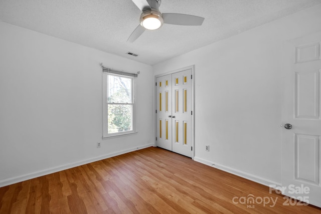 unfurnished bedroom featuring ceiling fan, a closet, a textured ceiling, and light hardwood / wood-style flooring