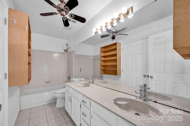 full bathroom with tiled shower / bath, tile patterned flooring, vanity, toilet, and a textured ceiling