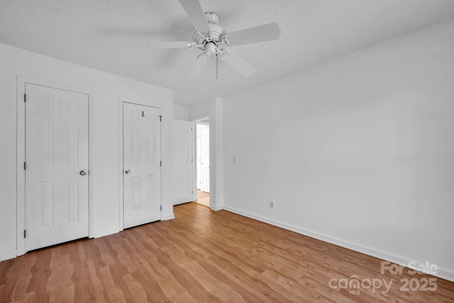 unfurnished bedroom with ceiling fan, a textured ceiling, and light wood-type flooring