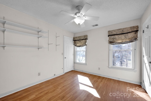 unfurnished room with ceiling fan, light hardwood / wood-style floors, and a textured ceiling