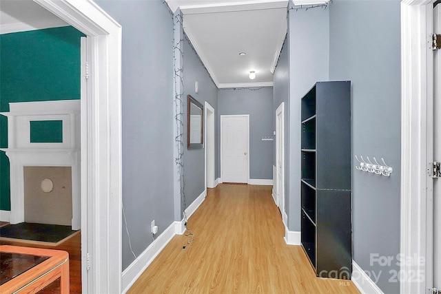 corridor with ornamental molding and light hardwood / wood-style flooring