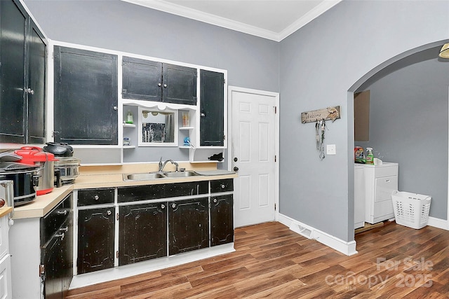 kitchen featuring sink, crown molding, washer and clothes dryer, and hardwood / wood-style floors