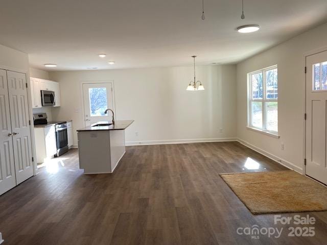 kitchen featuring appliances with stainless steel finishes, dark hardwood / wood-style floors, pendant lighting, white cabinetry, and sink