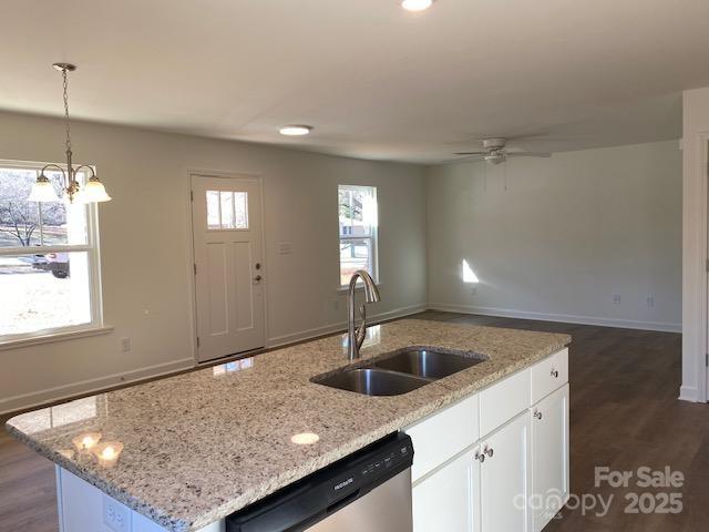 kitchen featuring sink, white cabinetry, light stone counters, dishwasher, and a kitchen island with sink