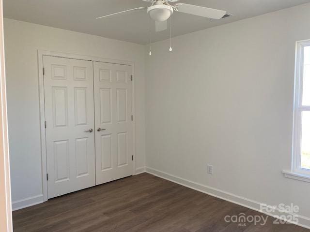 unfurnished bedroom featuring dark hardwood / wood-style floors, ceiling fan, and a closet