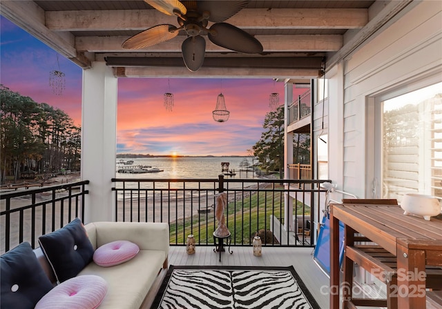 balcony at dusk with ceiling fan and a water view