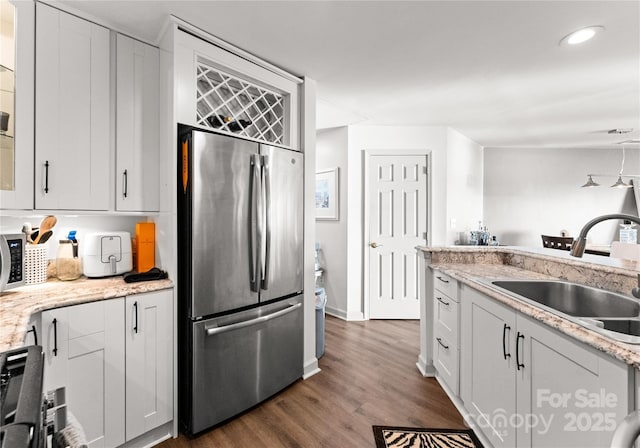 kitchen with dark wood finished floors, freestanding refrigerator, white cabinetry, a sink, and recessed lighting