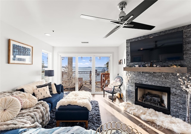 living area with visible vents, a stone fireplace, and wood finished floors