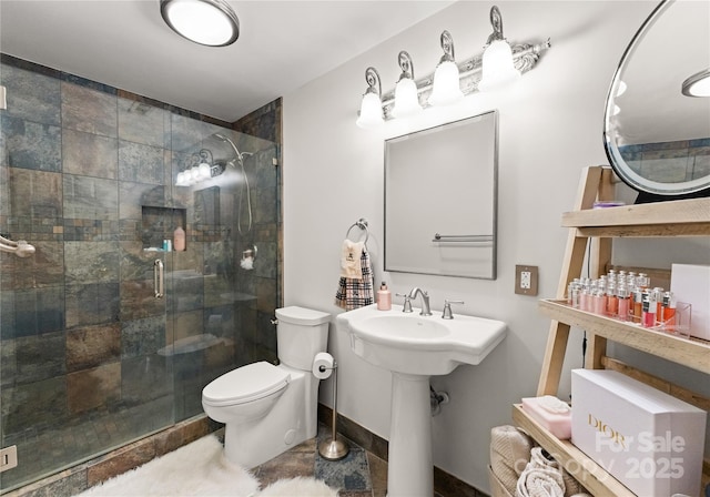 bathroom with a shower stall, toilet, and baseboards