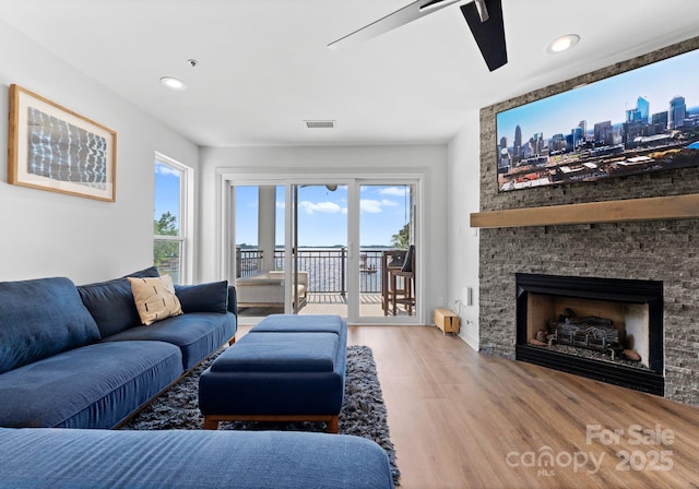 living area with wood finished floors, ceiling fan, a fireplace, visible vents, and recessed lighting