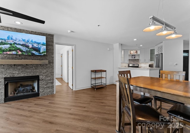 dining space with recessed lighting, wood finished floors, a fireplace, and baseboards