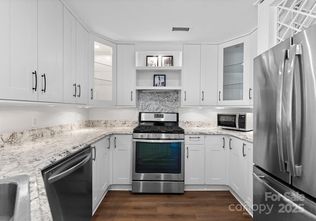 kitchen with white cabinets, light stone countertops, dark wood-style flooring, and stainless steel appliances