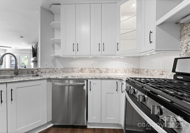 kitchen featuring open shelves, a sink, white cabinets, appliances with stainless steel finishes, and light stone countertops