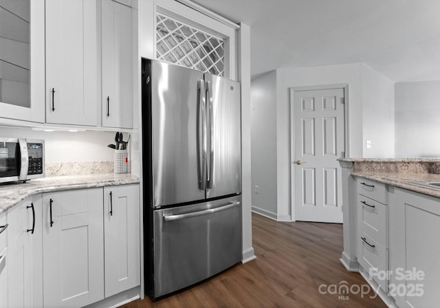 kitchen featuring light stone counters, dark wood-type flooring, glass insert cabinets, appliances with stainless steel finishes, and white cabinetry