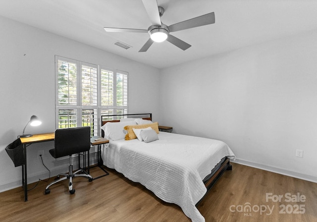bedroom featuring wood finished floors, visible vents, a ceiling fan, and baseboards