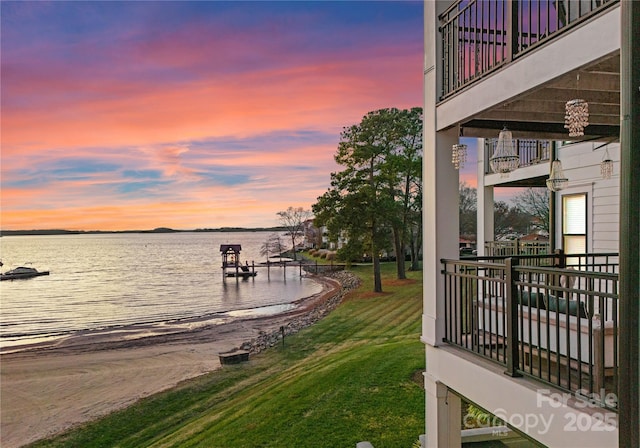 view of dock with a balcony, a yard, and a water view