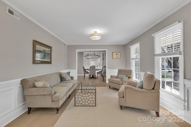 living room with crown molding, a notable chandelier, and light hardwood / wood-style flooring