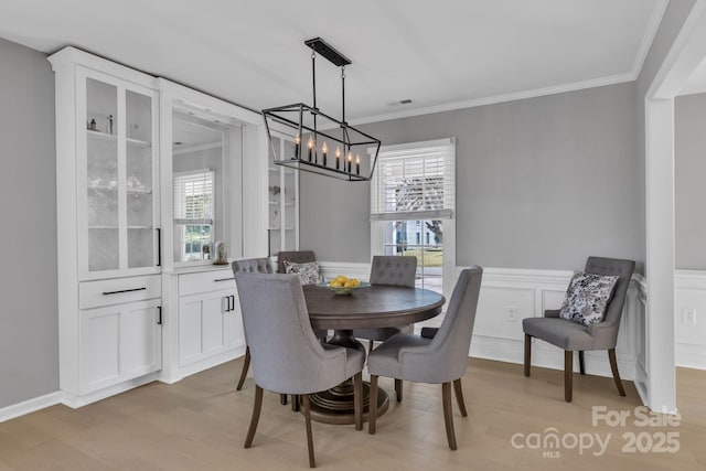 dining area featuring plenty of natural light, ornamental molding, and light hardwood / wood-style floors