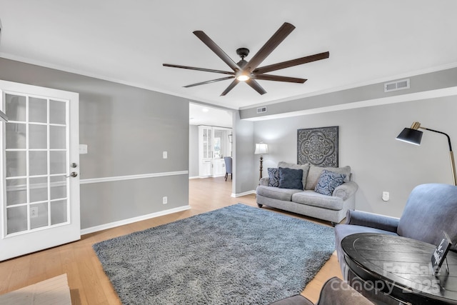 living room with crown molding, ceiling fan, and light hardwood / wood-style floors