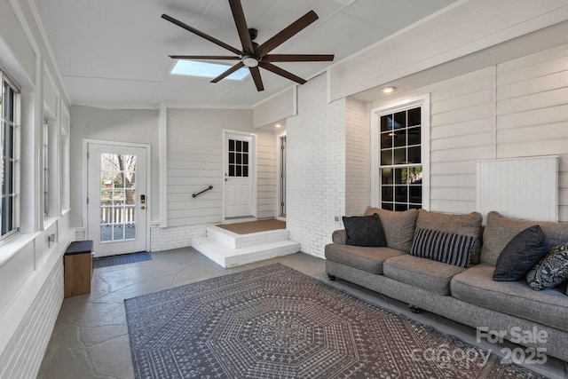 sunroom featuring ceiling fan and vaulted ceiling with skylight