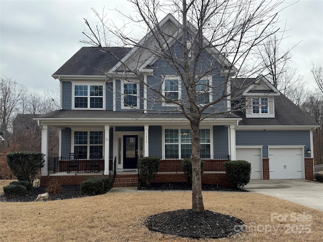 view of property featuring a garage, a front lawn, and covered porch