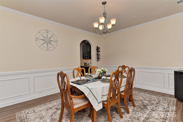 dining space with dark hardwood / wood-style flooring, crown molding, and an inviting chandelier