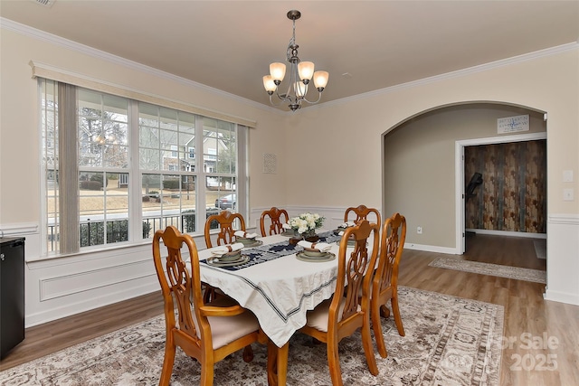 dining area with an inviting chandelier, ornamental molding, and wood-type flooring