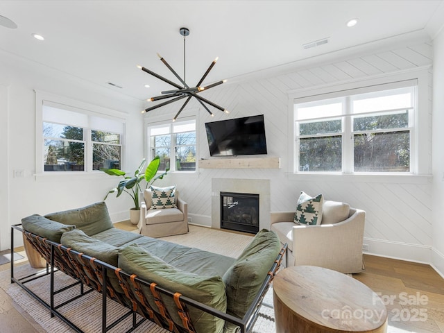 living room featuring ornamental molding, an inviting chandelier, and light hardwood / wood-style floors