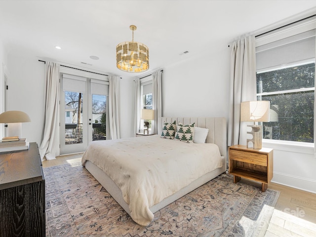 bedroom with an inviting chandelier, access to exterior, hardwood / wood-style floors, and french doors